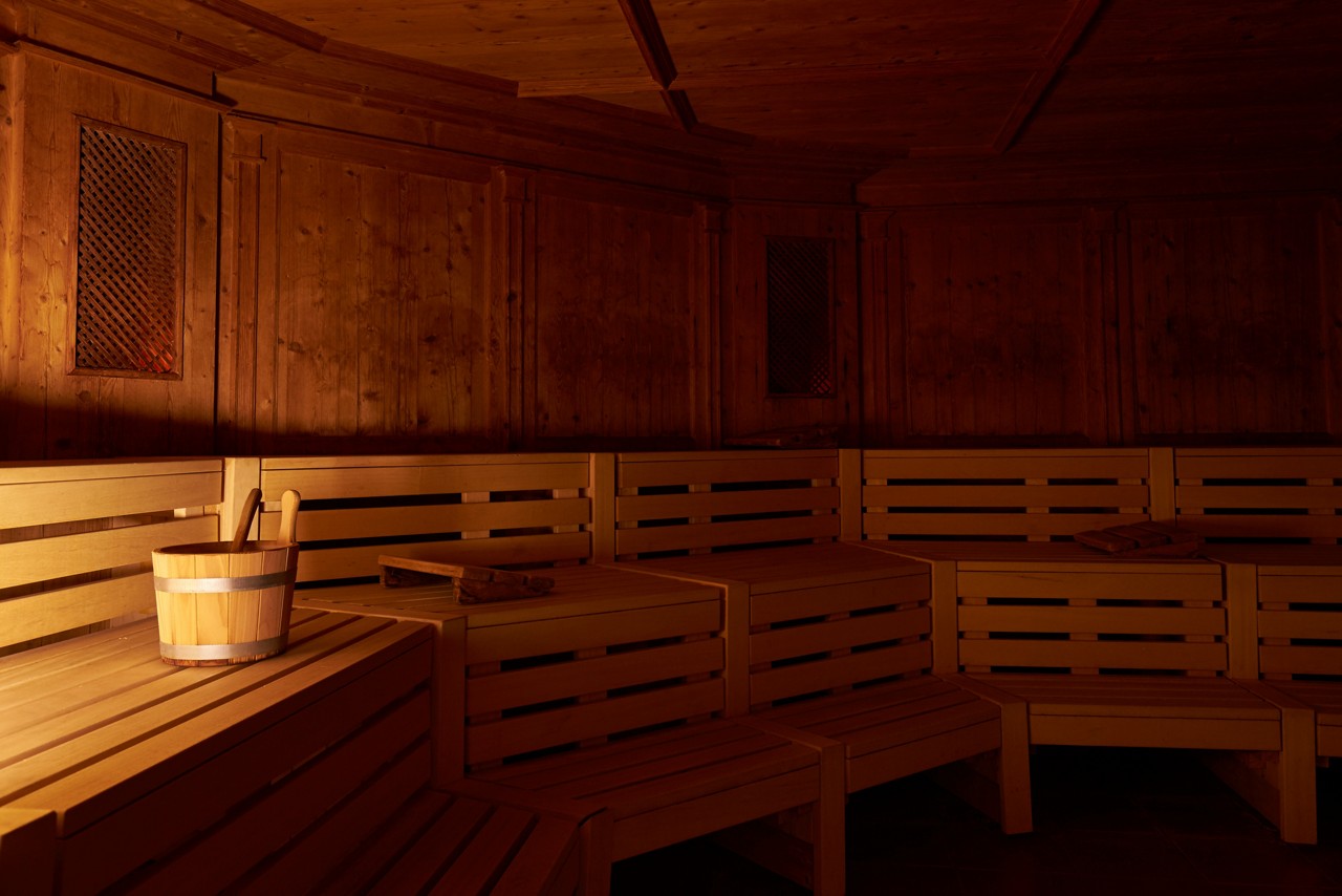Wooden Tyrolean Sauna with bench seating and a bucket of cold water.